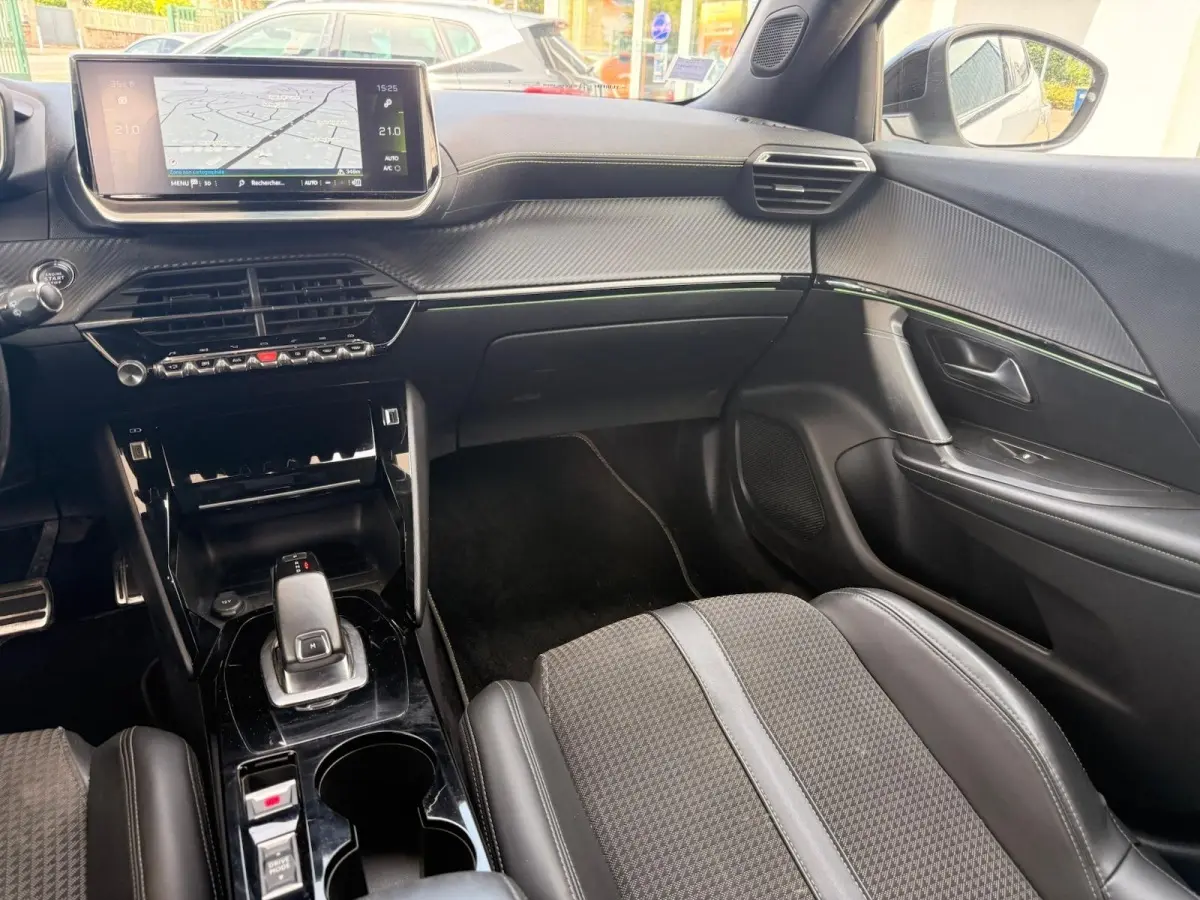 Vue intérieure côté passager du Peugeot 2008 blanc, mettant en valeur la console centrale moderne et l'écran tactile intégré.