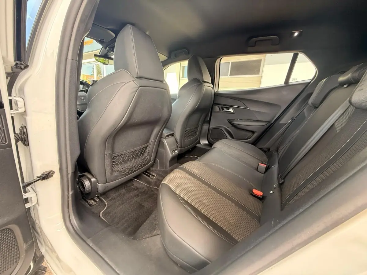 Vue intérieure côté gauche arrière du Peugeot 2008 blanc, mettant en valeur la banquette tri-matière et les filets au dos des sièges avant.
