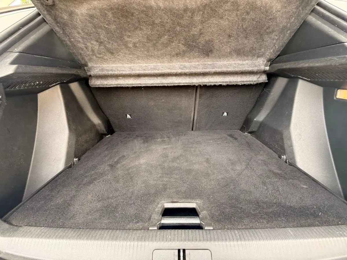 Vue intérieure du coffre ouvert d'un Peugeot 2008 blanc, montrant le plancher et la moquette noire du compartiment.