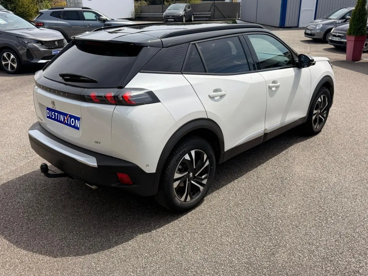 Peugeot 2008 blanc en 3/4 arrière droit, toit noir contrasté et feux arrière à effet griffes rouges.