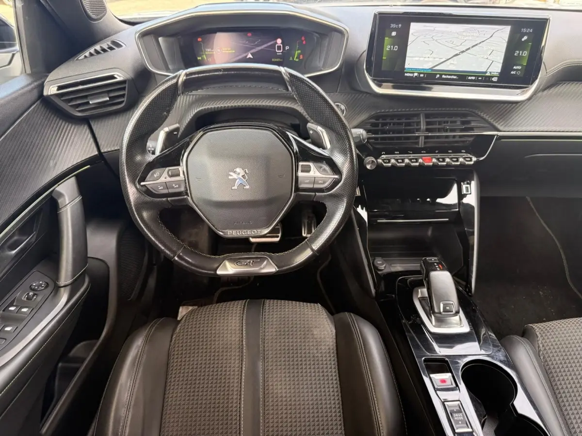 Vue intérieure frontale du poste de conduite du Peugeot 2008 GT 2021 avec volant compact, écran tactile et sellerie tri-matière noire.