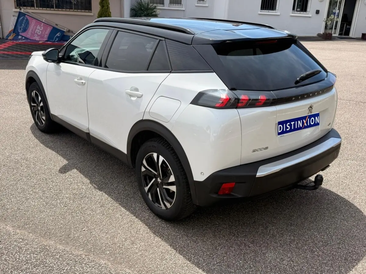 Vue 3/4 arrière droite d’un Peugeot 2008 blanc 2021 avec toit noir, feux arrière à LED et attelage visible.