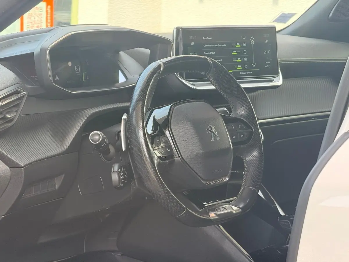 Vue intérieure du poste de conduite du Peugeot 2008 blanc, avec volant compact et écran tactile central visible.
