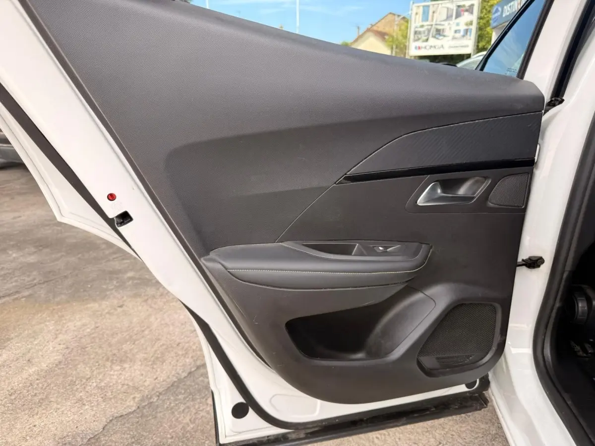 Vue rapprochée de la porte arrière droite blanche d’un Peugeot 2008 2021 avec garniture intérieure noire et surpiqûres grises.