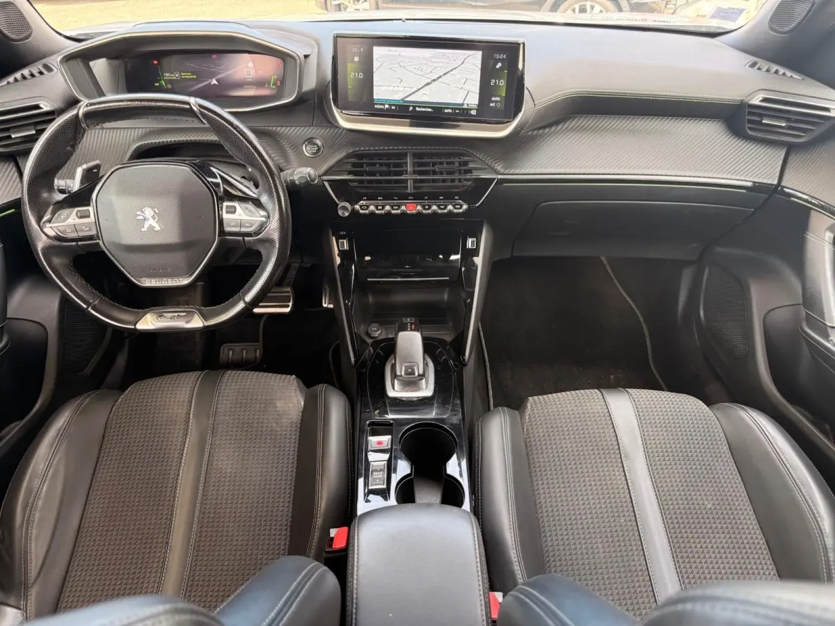 Vue intérieure avant du Peugeot 2008 blanc de 2021, montrant le tableau de bord, volant compact et écran tactile central.