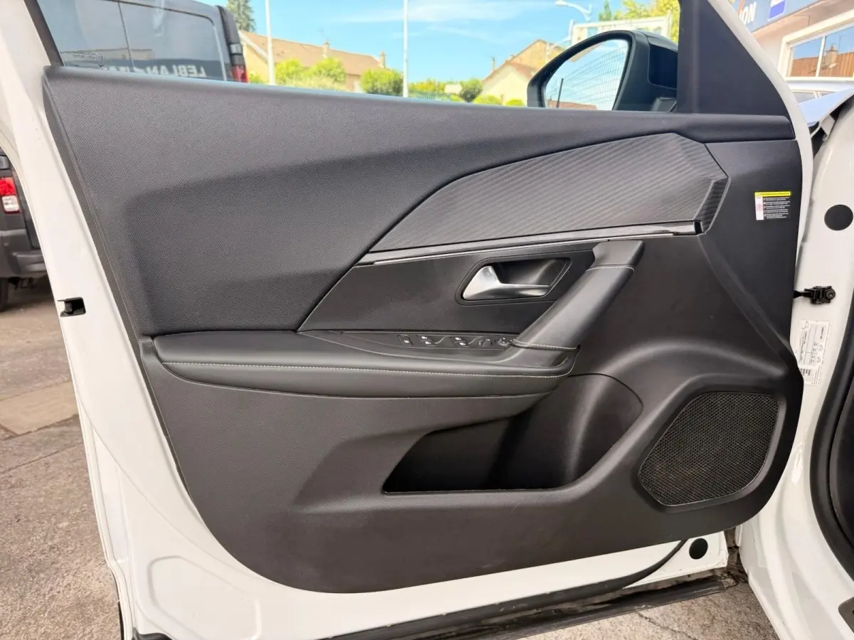 Vue intérieure côté gauche de la porte avant blanche du Peugeot 2008 avec garniture noire et surpiqûres vertes.