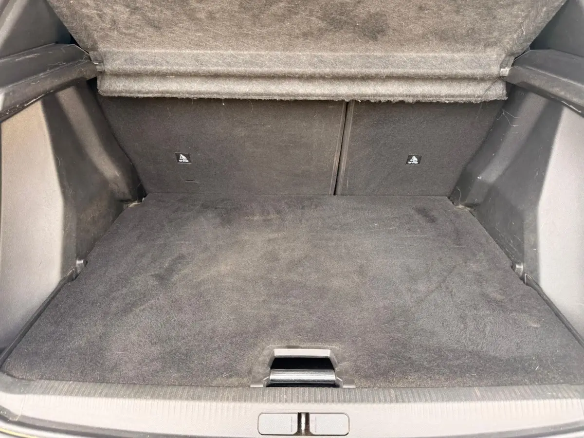 Coffre ouvert du Peugeot 2008 blanc, vue intérieure montrant le tapis de sol et la banquette arrière rabattue.