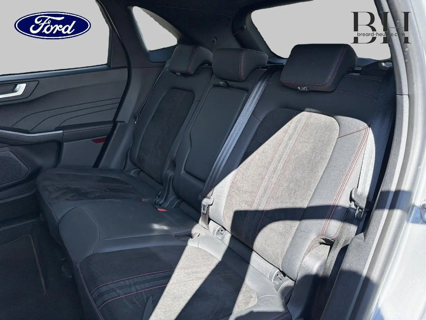 Vue intérieure de la banquette arrière du Ford Kuga 2024, sièges en suédine noire avec surpiqûres rouges.
