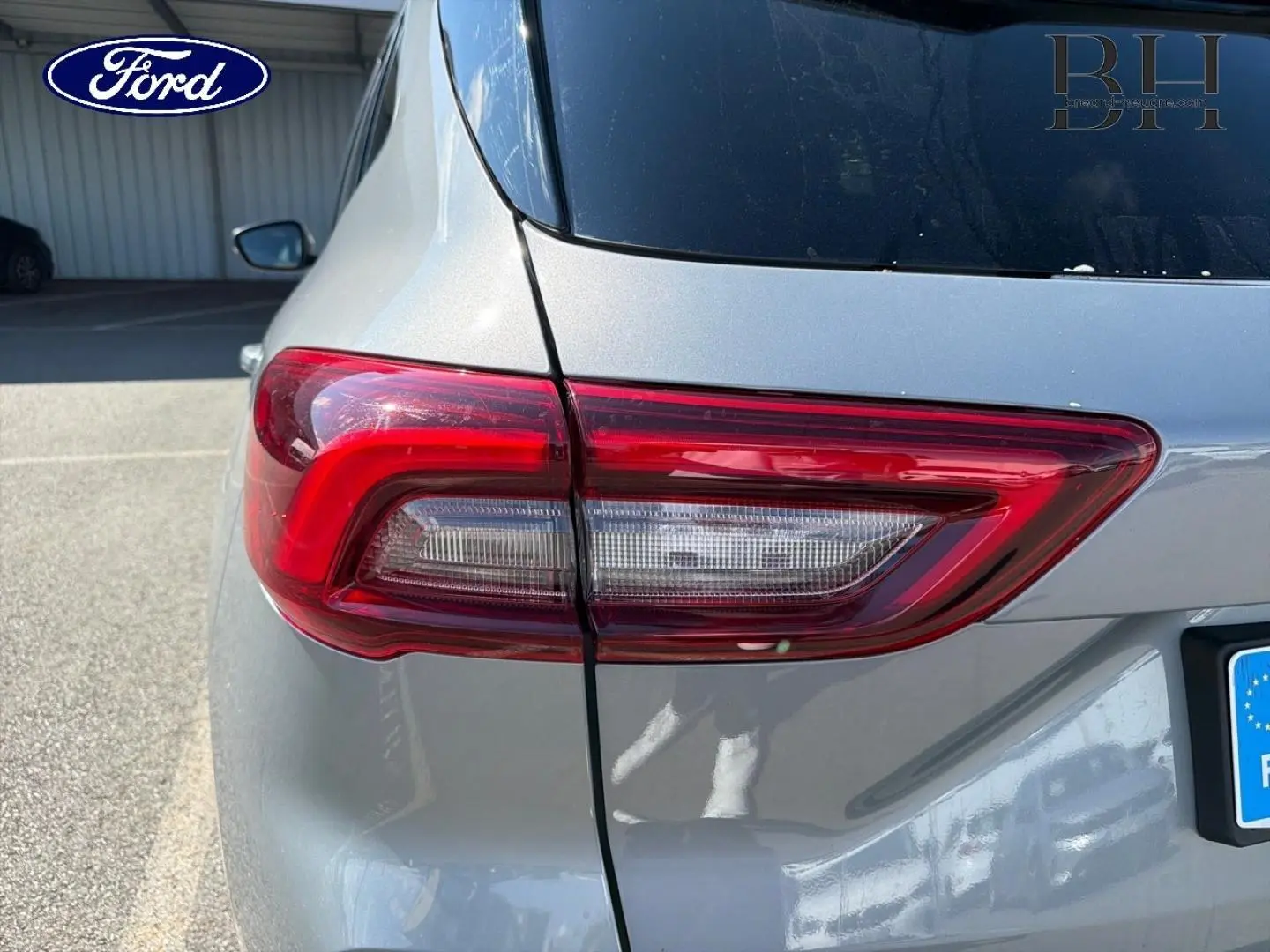 Gros plan sur le feu arrière gauche d’un Ford Kuga gris Solar métallisé, avec partie de la lunette arrière visible.