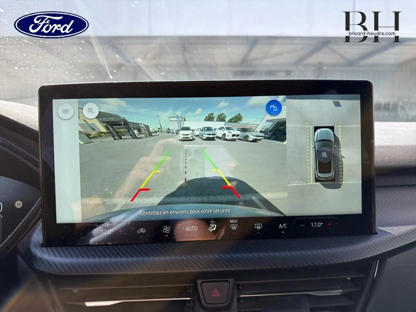Écran tactile intérieur du Ford Kuga 2024 montrant la caméra de recul avec vue panoramique et aide au stationnement.