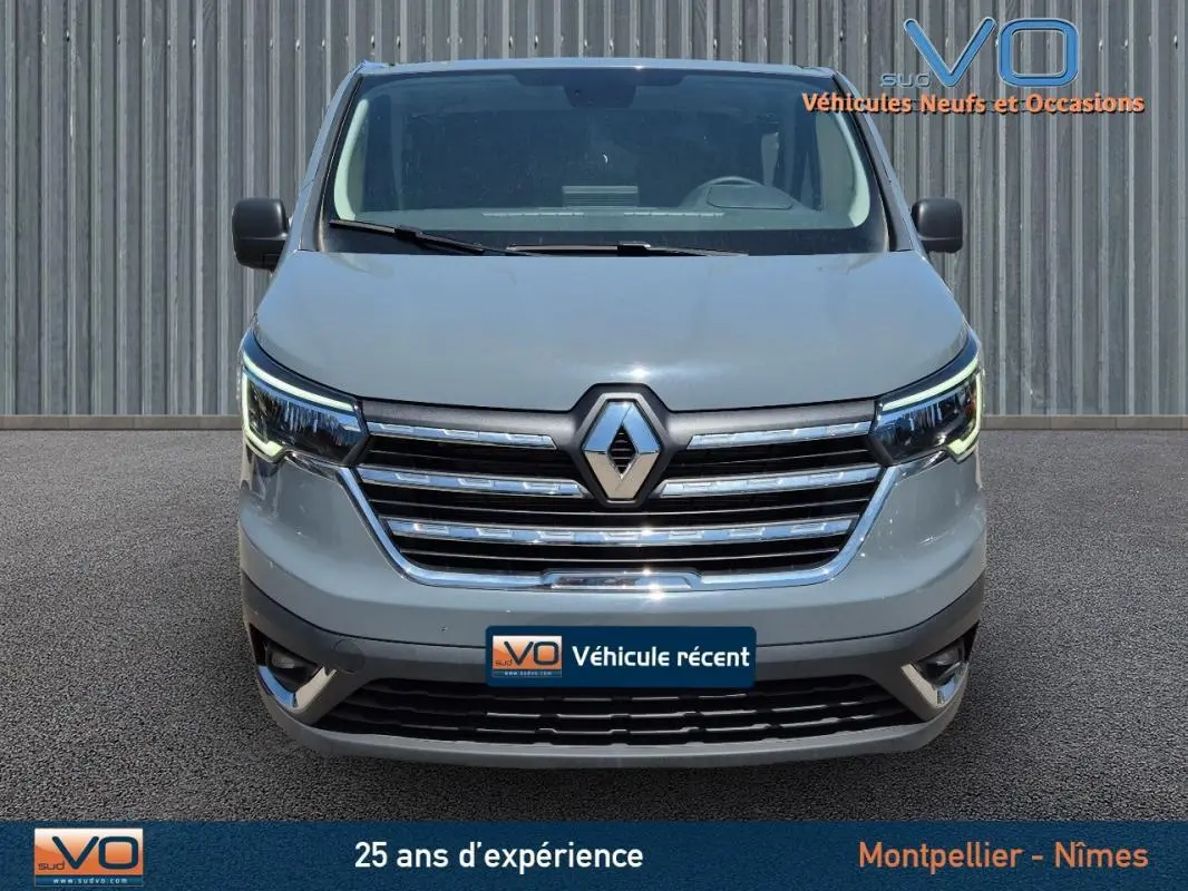 Vue frontale du Renault Trafic Fourgon gris foncé 2023 avec calandre chromée et feux LED allumés.