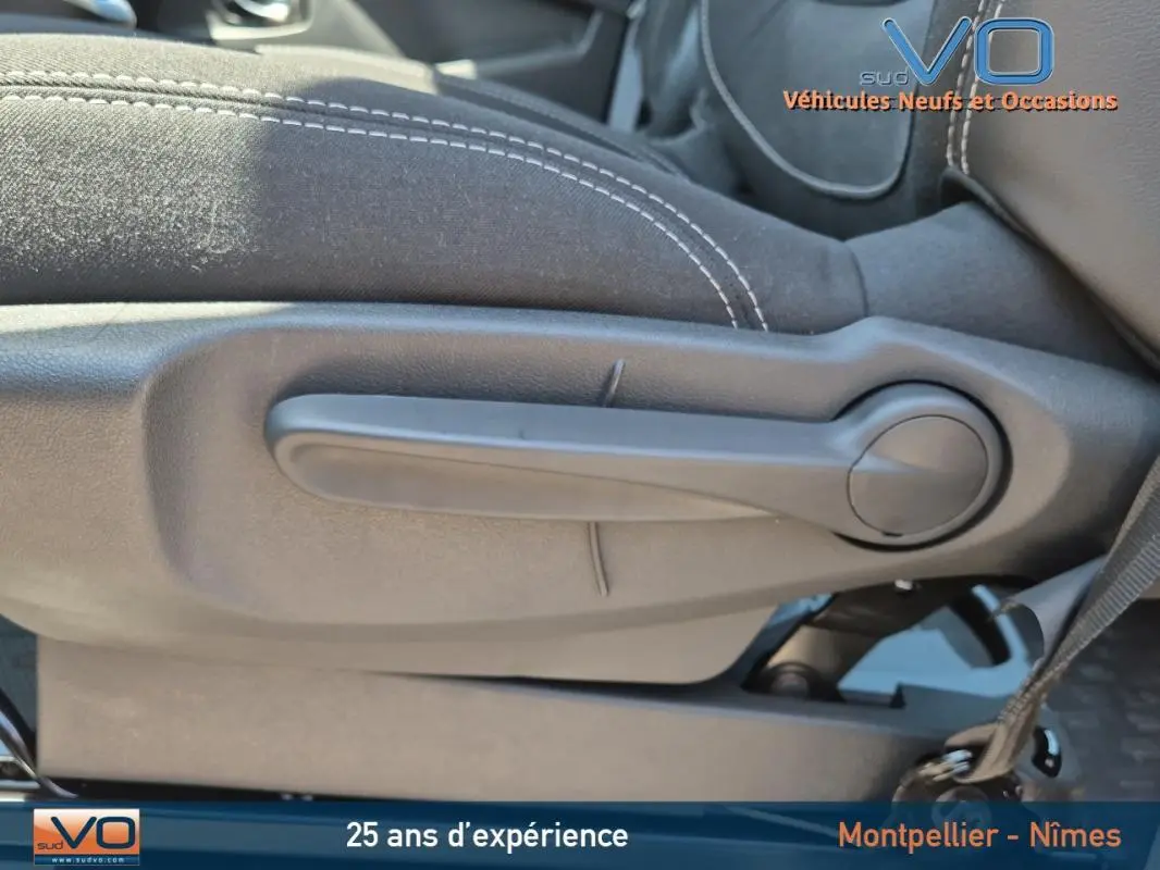 Levier de réglage manuel du siège avant en tissu noir avec surpiqûres blanches dans un Renault Trafic Fourgon gris foncé 2023.