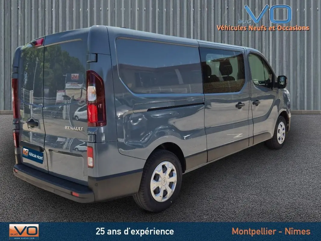 Vue 3/4 arrière droite d'un Renault Trafic Fourgon gris foncé avec porte latérale et vitres surteintées.
