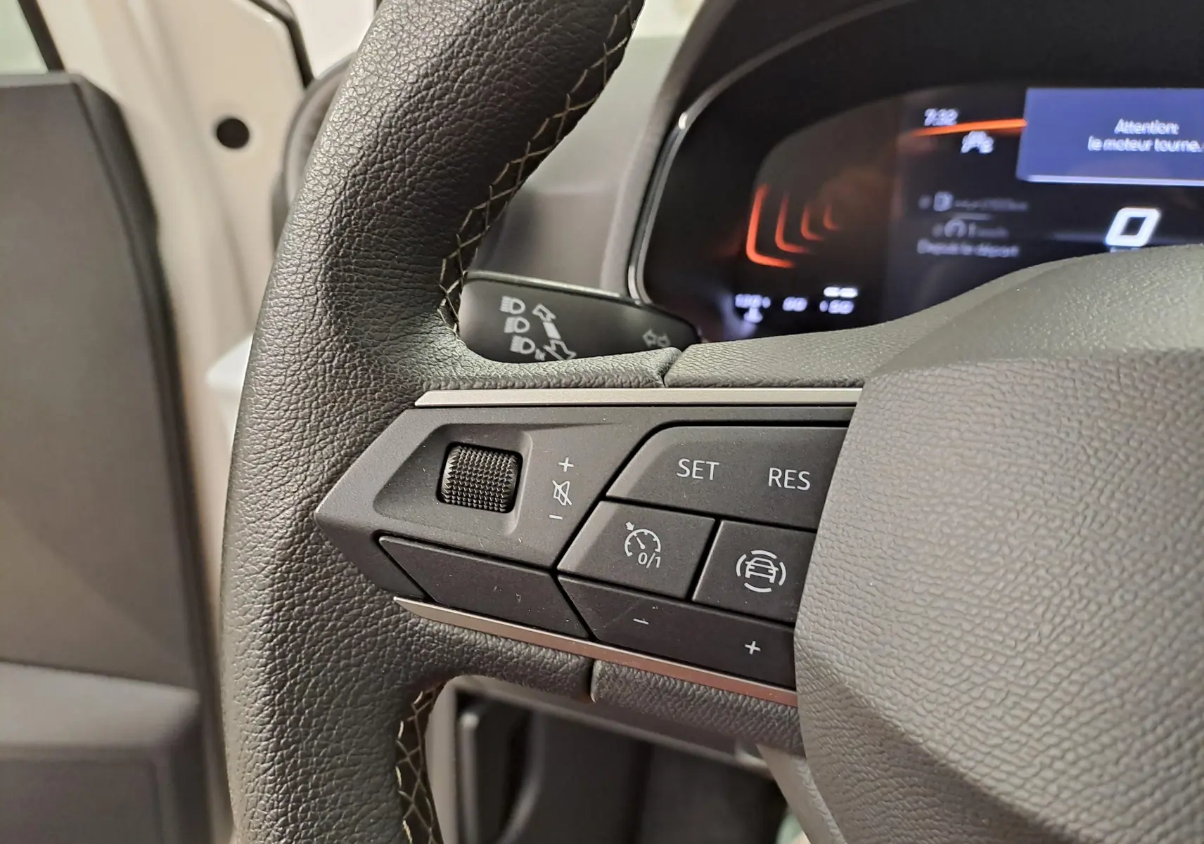 Gros plan sur les commandes au volant gauche de la SEAT Ibiza 2023 blanc candy, affichage numérique en arrière-plan.