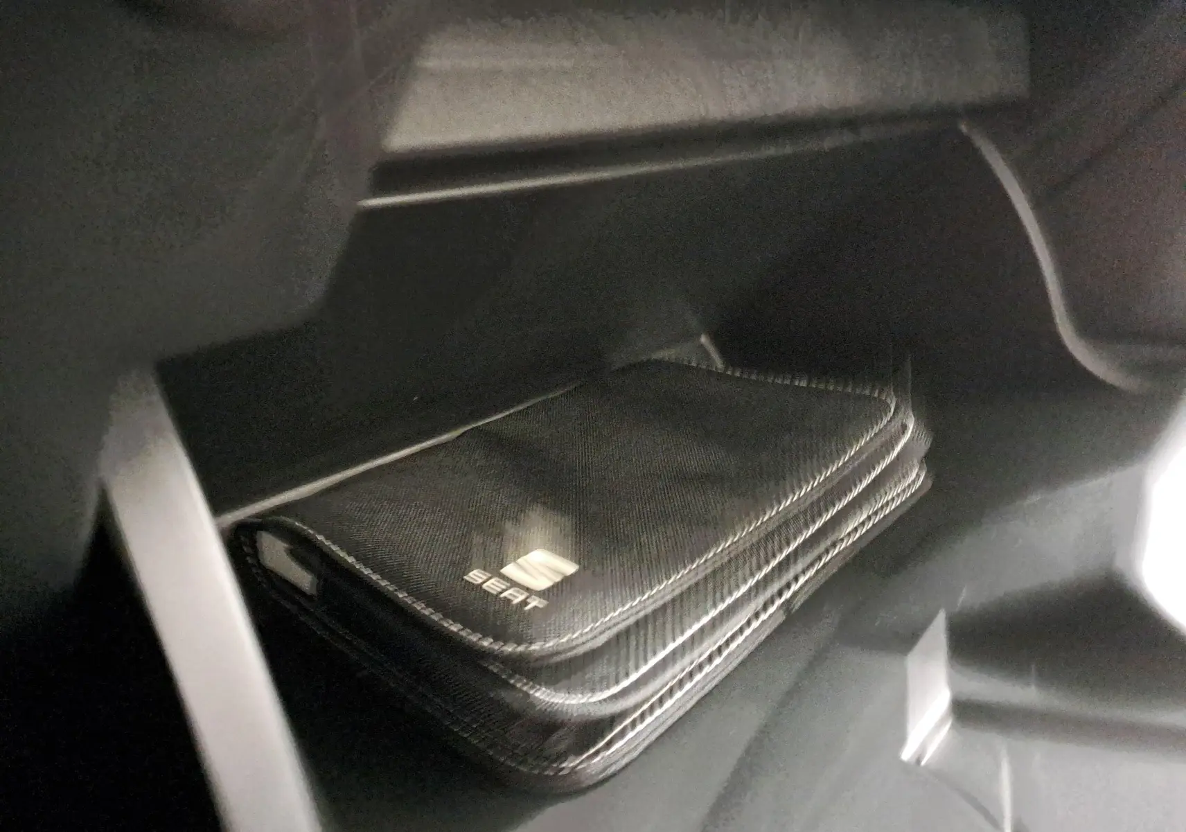 Pochette noire avec logo SEAT dans la boîte à gants d'une SEAT Ibiza blanc candy 2023, version Style Business.