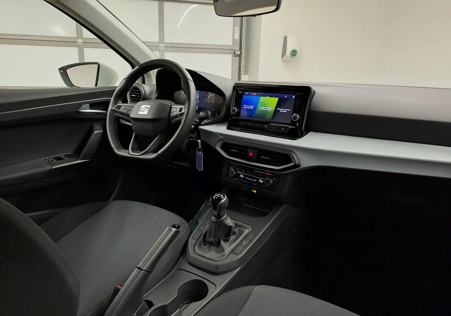 Intérieur de la SEAT Ibiza 2023 vue côté conducteur, tableau de bord moderne avec écran tactile et boîte manuelle noire.