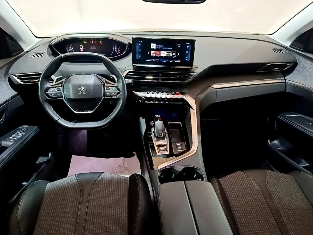 Vue intérieure avant du Peugeot 3008 gris foncé, tableau de bord moderne avec écran tactile et volant cuir multifonctions.