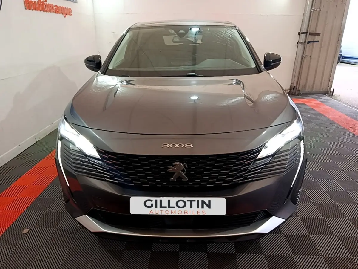 Vue avant d'un Peugeot 3008 gris foncé 2022 avec phares LED allumés et calandre noire distinctive.