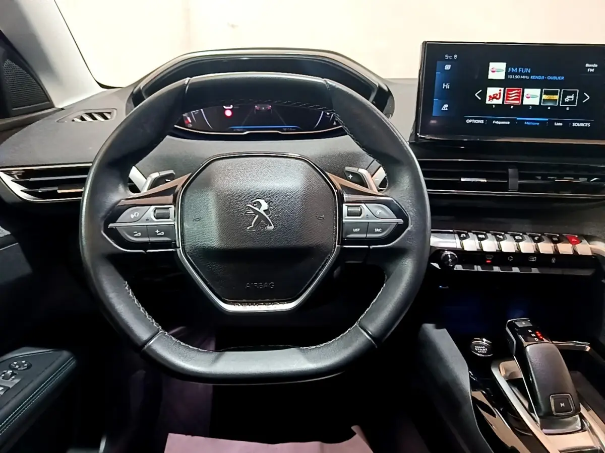 Vue intérieure centrée sur le volant cuir et tableau de bord tactile du Peugeot 3008 gris foncé 2022 Allure Pack.