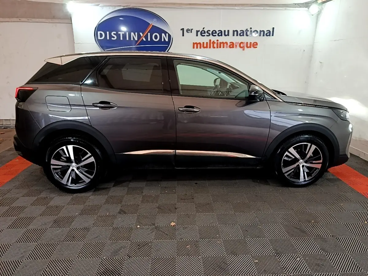 Profil côté droit du Peugeot 3008 gris foncé 2022 avec jantes alliage et vitres teintées dans un showroom.