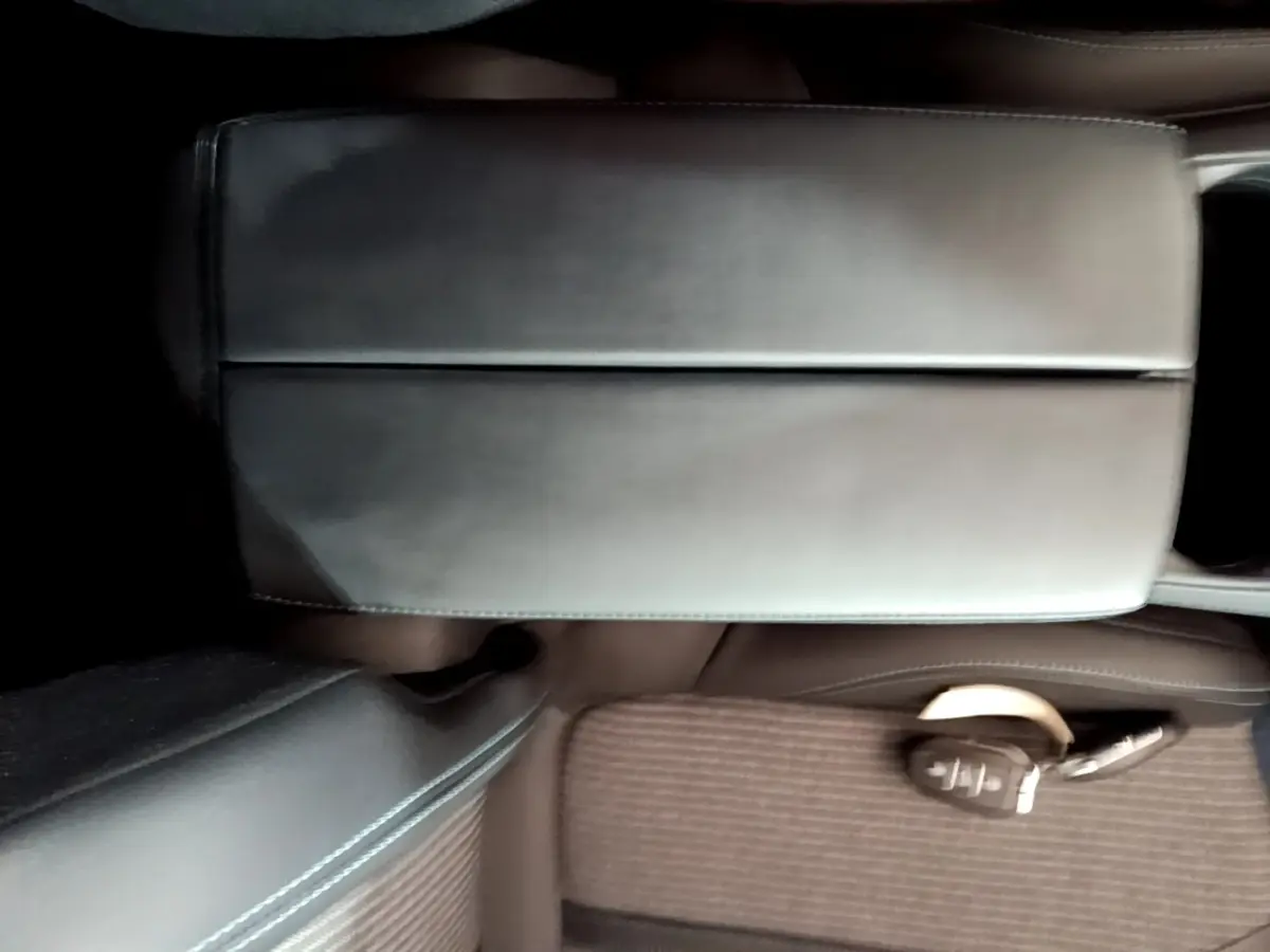 Gros plan sur l'accoudoir central en cuir noir et la clé intelligente posée sur le siège marron du Peugeot 3008 2022.