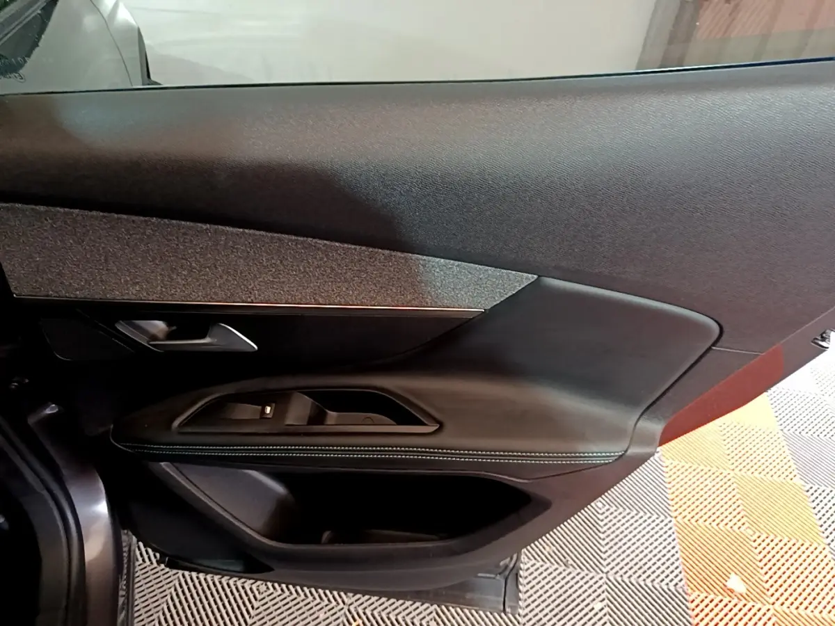 Gros plan sur la porte côté gauche du Peugeot 3008 gris foncé, mettant en valeur les commandes de vitre et la poignée intérieure.