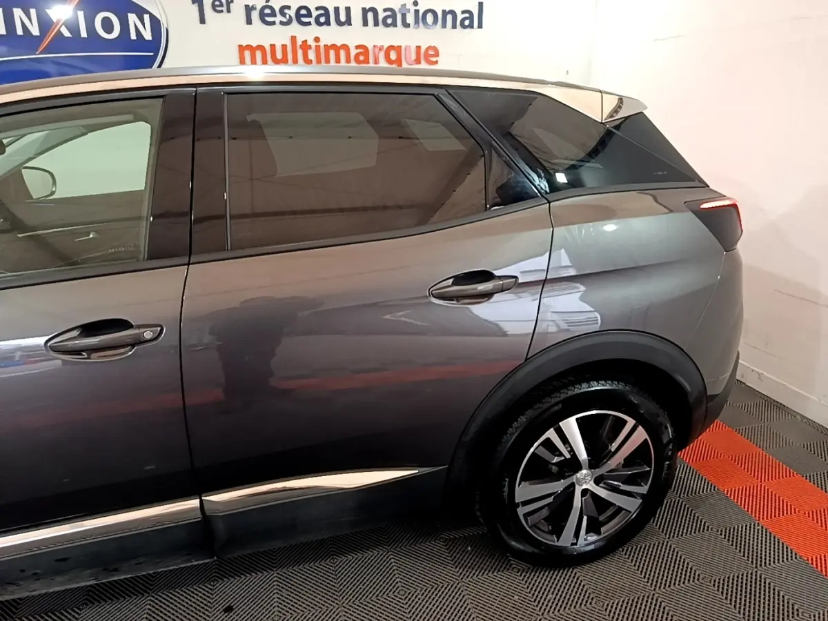 Vue latérale côté droit du Peugeot 3008 gris foncé avec jante alliage et vitres teintées en arrière-plan showroom.