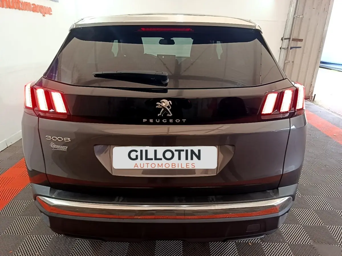 Vue arrière d'un Peugeot 3008 gris foncé avec feux LED caractéristiques et logo central sur hayon noir brillant.