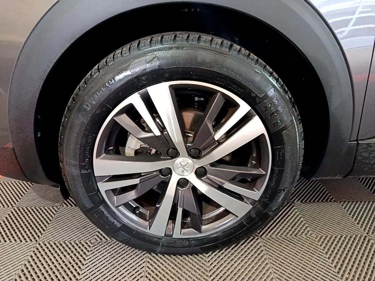 Gros plan sur la roue avant droite avec jante alliage du Peugeot 3008 gris foncé 2022.