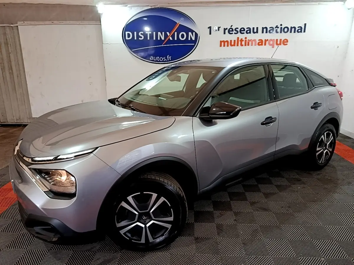 Vue 3/4 avant droite d'une Citroën C4 gris foncé avec phares allumés et jantes alliage distinctives.