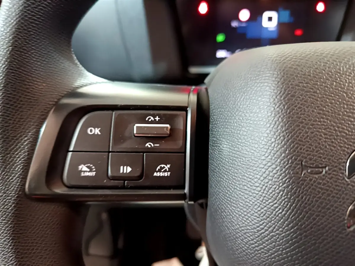 Gros plan sur les commandes multifonctions à gauche du volant noir de la Citroën C4 gris foncé, version 2021.