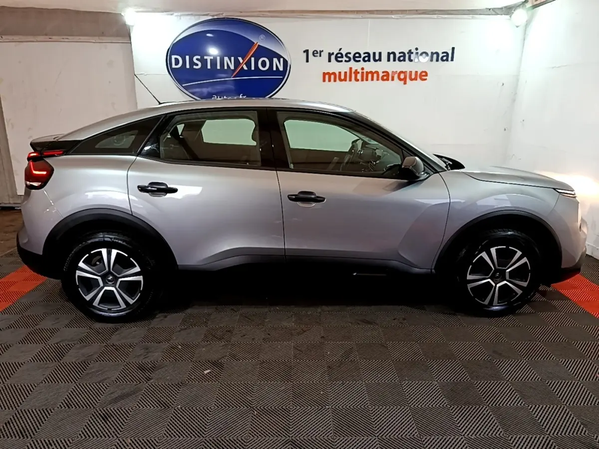 Vue de profil côté gauche d'une Citroën C4 gris foncé 2021 avec jantes alliage et feux arrière LED allumés.