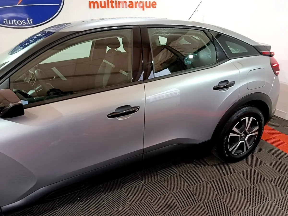 Vue latérale côté gauche d'une Citroën C4 gris foncé, mettant en valeur les lignes fluides et les jantes au design moderne.