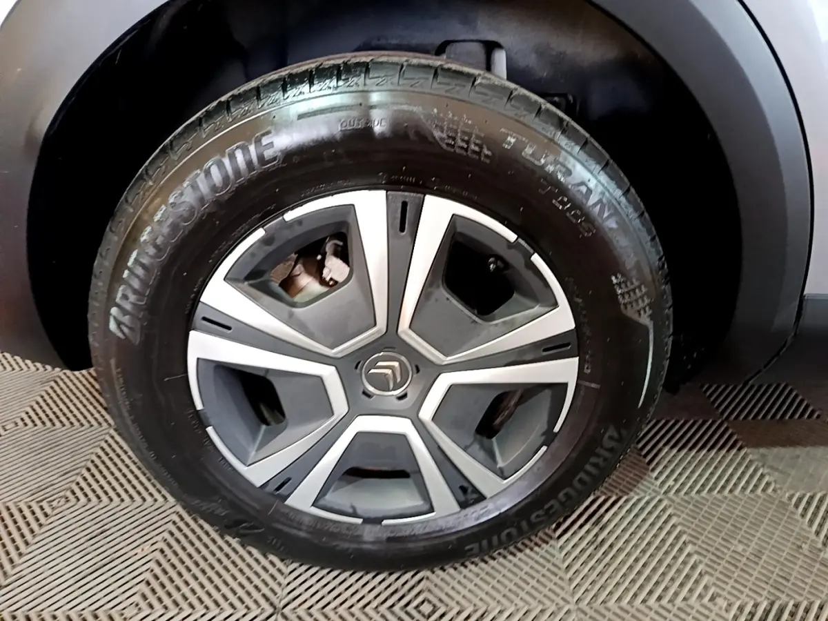 Gros plan sur la roue avant droite d'une Citroën C4 gris foncé, avec jante alliage et pneu Bridgestone.