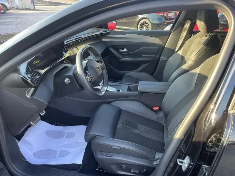 Vue intérieure côté conducteur du Peugeot 408 Hybrid 136 cv GT 2024 noir métal, avec sièges en cuir et tableau de bord moderne.