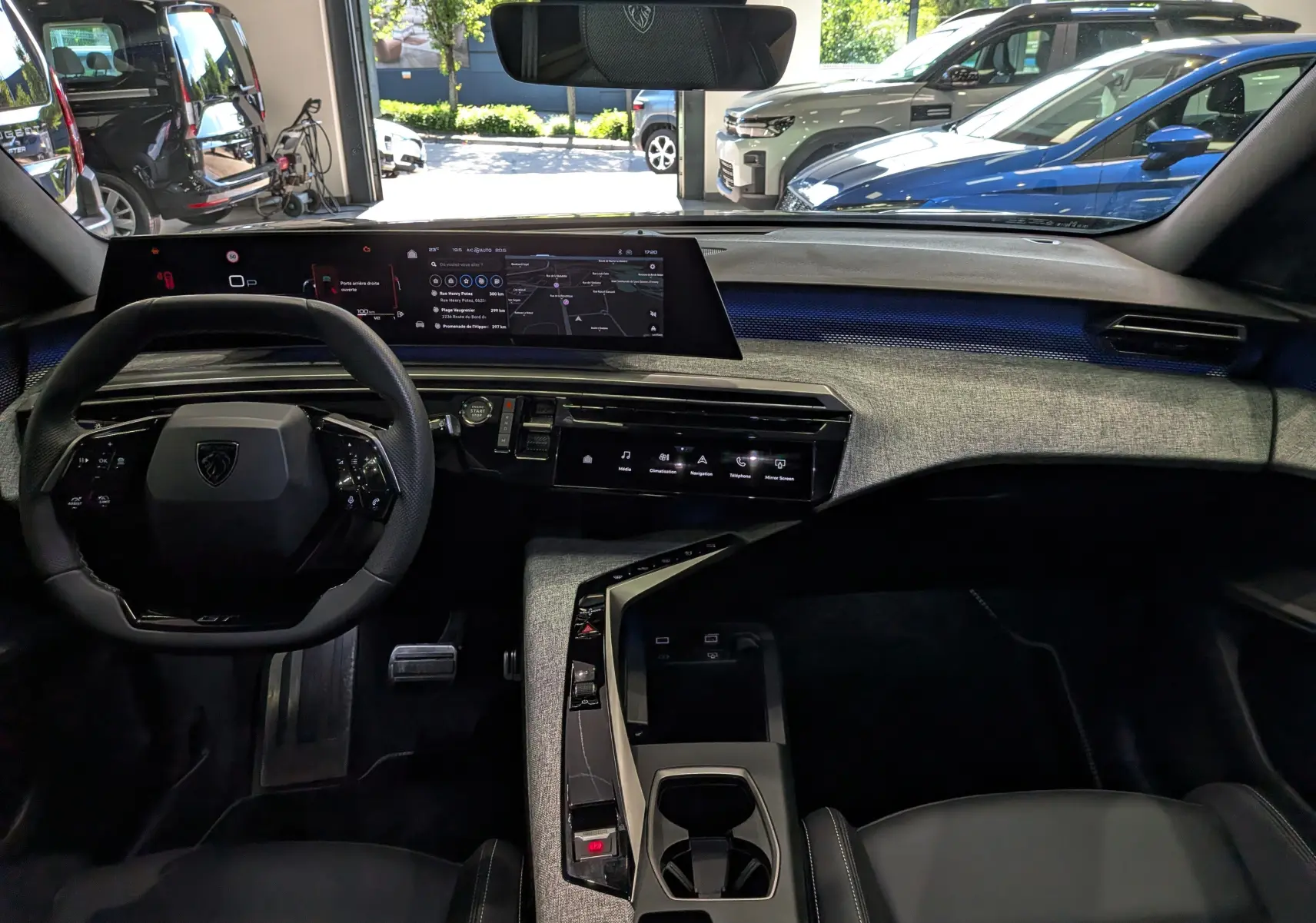 Vue intérieure avant du Peugeot 5008 Hybrid 145 GT 2025, tableau de bord moderne avec écran large et finition tissu gris.