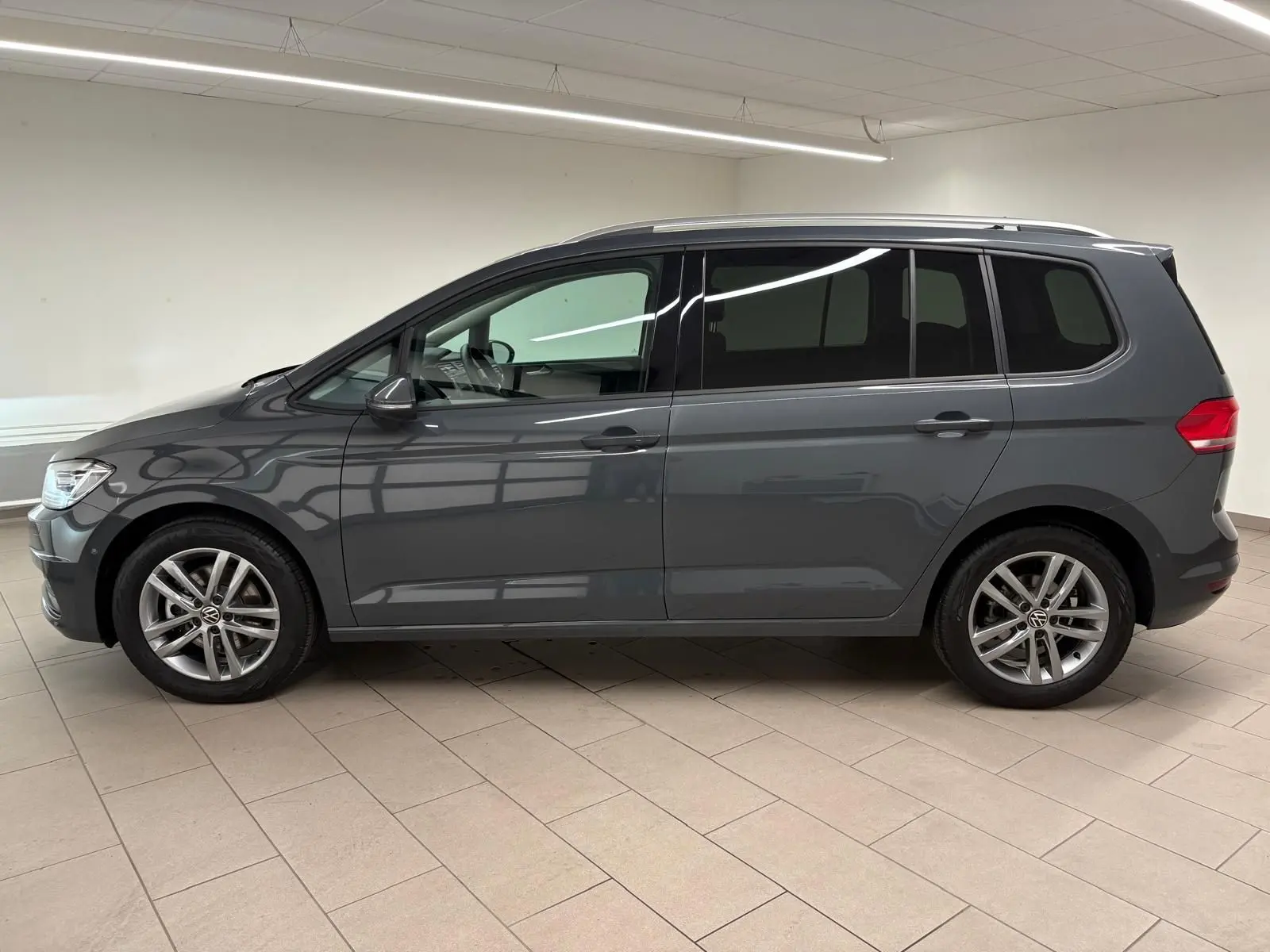Profil droit d'un Volkswagen Touran 2025 gris dauphin avec jantes alliage et vitres teintées en intérieur neutre.