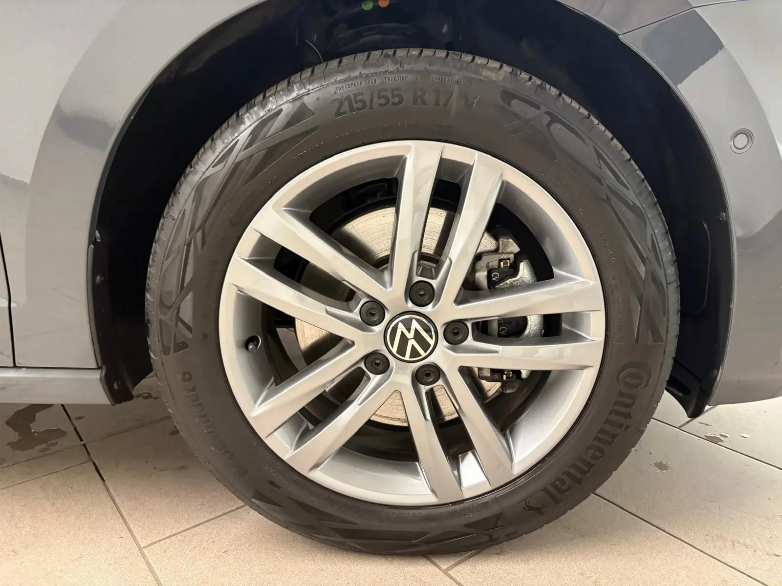 Gros plan sur la roue avant droite du Volkswagen Touran gris Dauphin, jante alliage et pneu Continental.