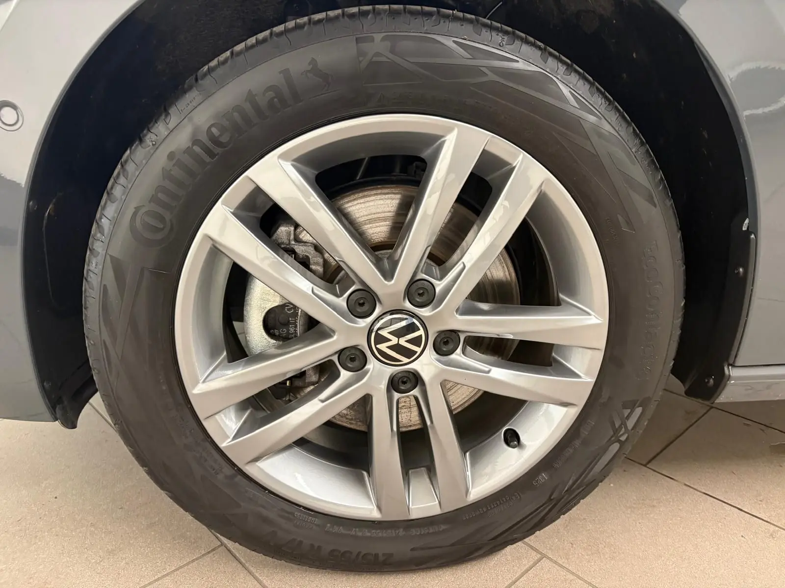 Gros plan sur la roue avant droite du Volkswagen Touran gris Dauphin, jante alliage 10 branches et pneu Continental.