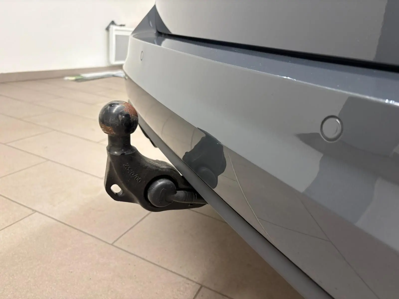 Gros plan sur l'attelage escamotable électrique du pare-chocs arrière gris dauphin du Volkswagen Touran 2025.