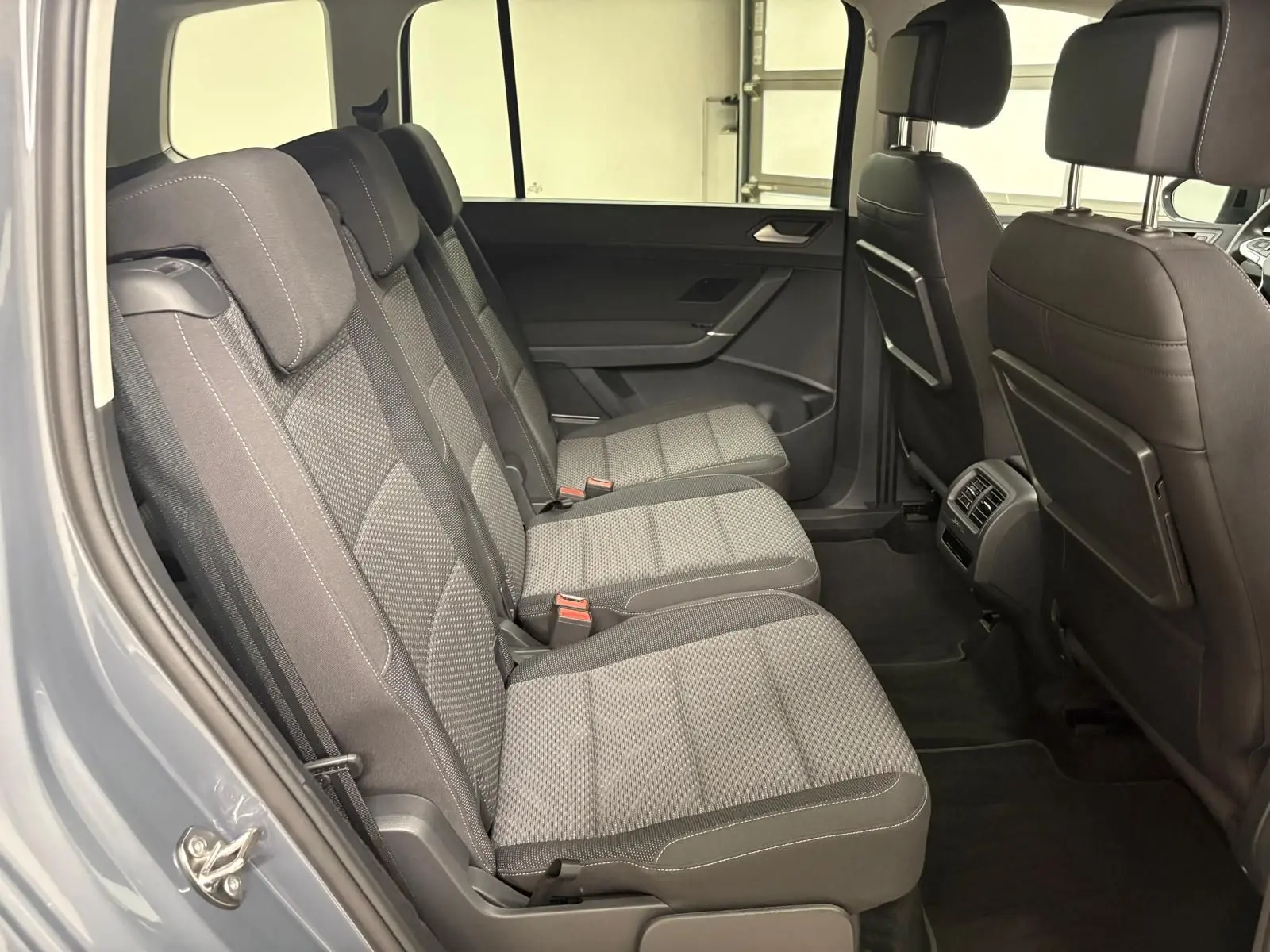 Vue latérale intérieure côté gauche montrant les trois sièges arrière gris avec appuie-têtes du Volkswagen Touran 2025.