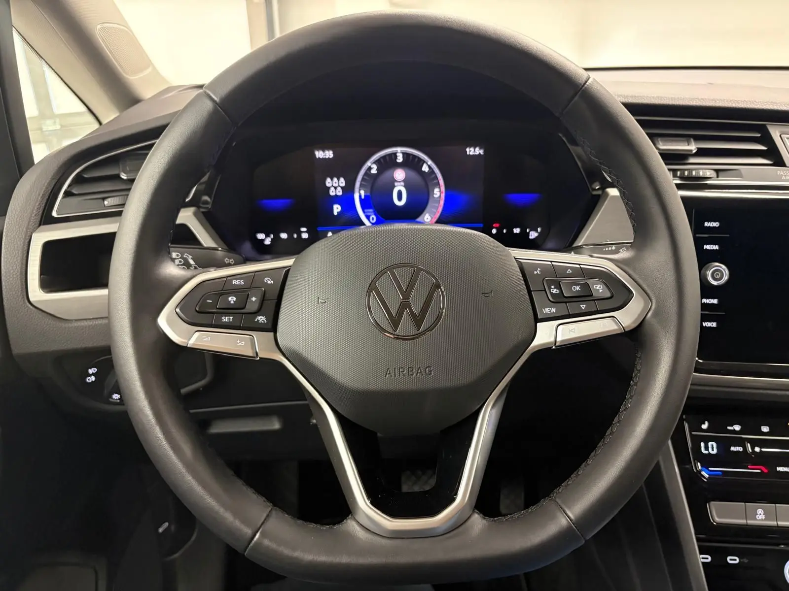 Vue frontale du volant cuir noir du Volkswagen Touran 2025 avec tableau de bord numérique et commandes intégrées.