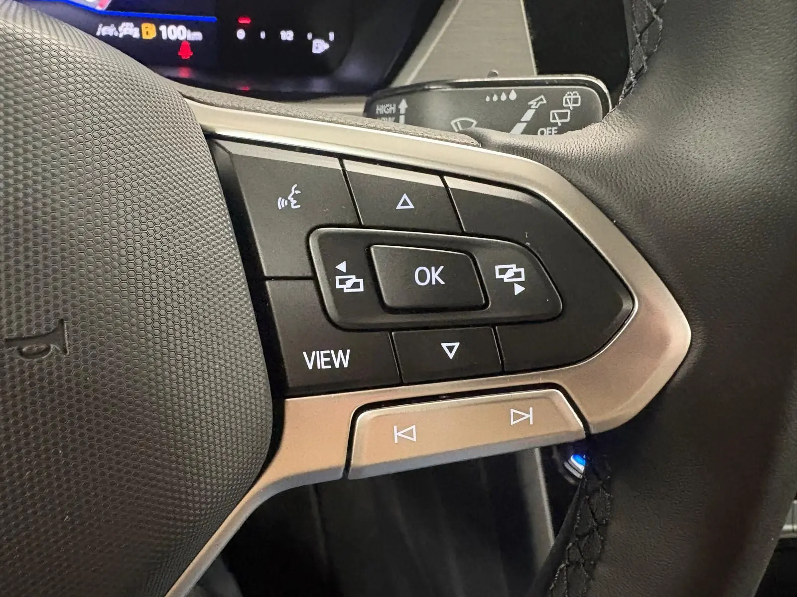 Gros plan sur les commandes multifonctions au volant du Volkswagen Touran 2025, finition VW Edition, avec boutons noirs et contour argenté.