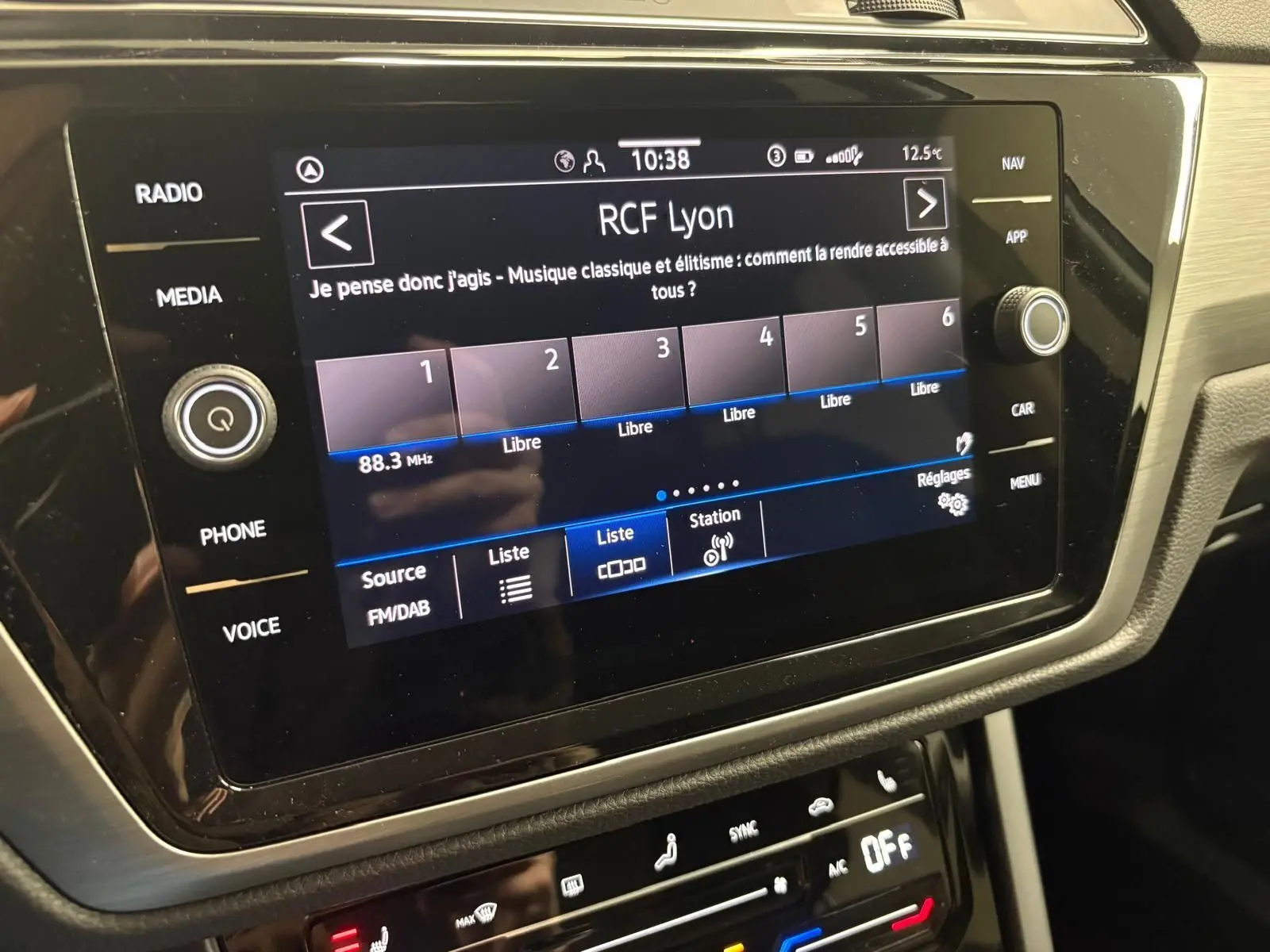 Écran tactile central du Volkswagen Touran 2025 affichant la radio RCF Lyon, avec commandes autour et finition intérieure noire.
