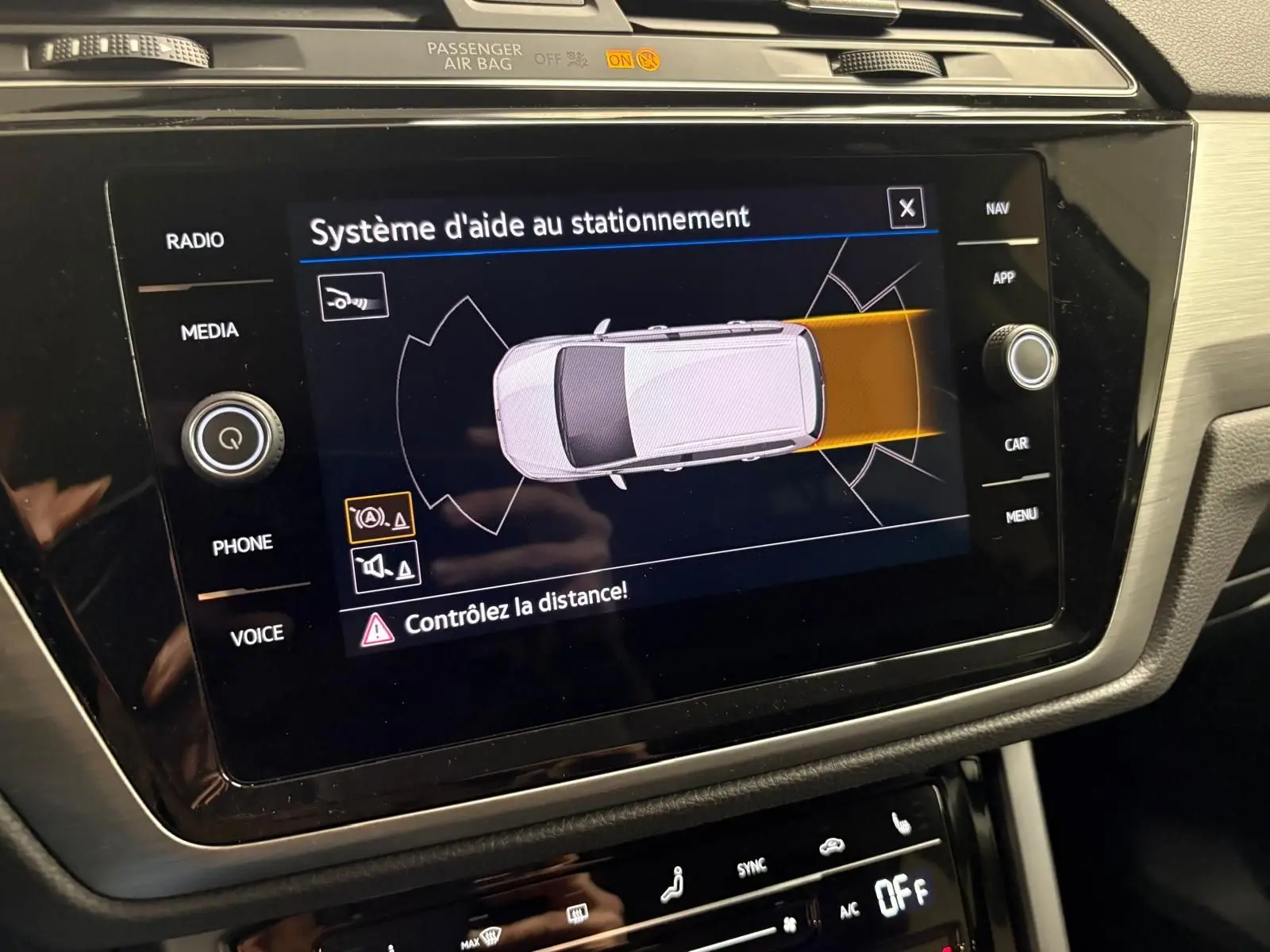Écran central du Volkswagen Touran 2025 affichant le système d'aide au stationnement avec visualisation du véhicule vue de dessus.