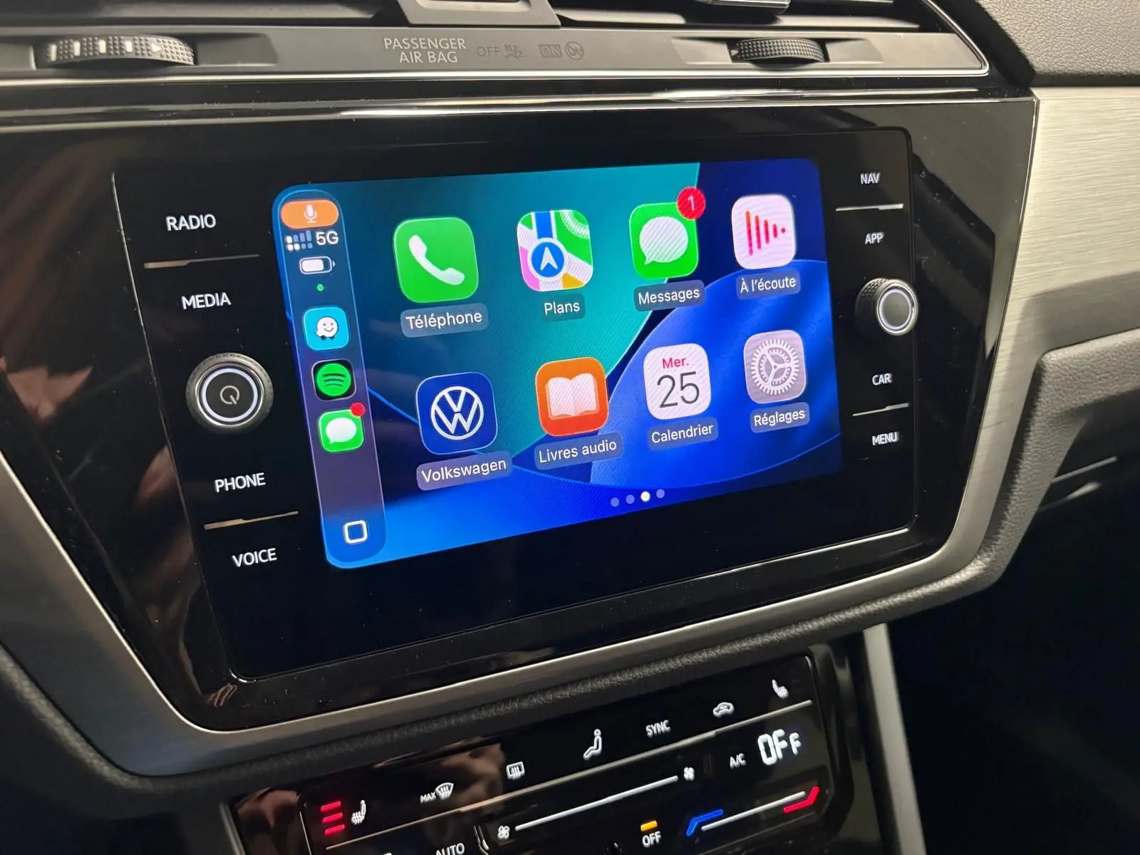 Écran tactile central du Volkswagen Touran 2025 affichant les applications Apple CarPlay, dans un intérieur noir et gris.