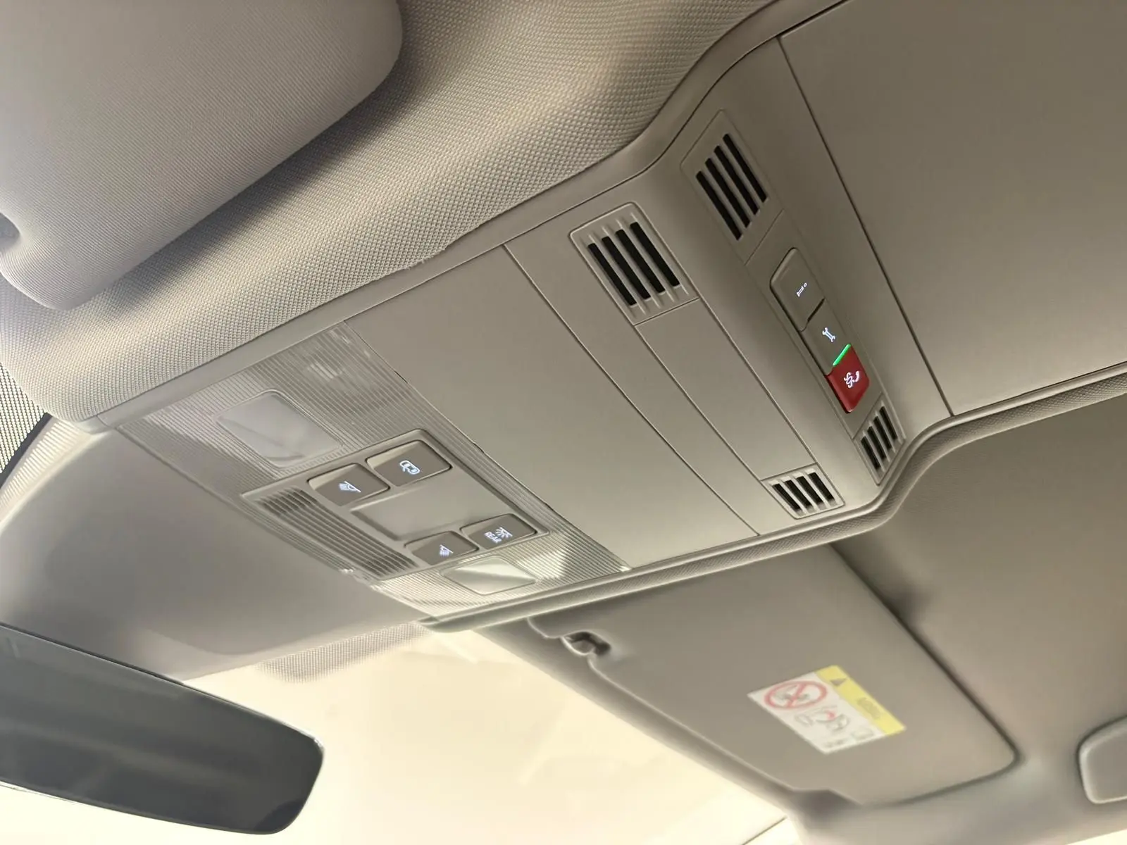 Vue intérieure du plafond avec commandes d'éclairage et ventilation du Volkswagen Touran 2025 gris Dauphin.