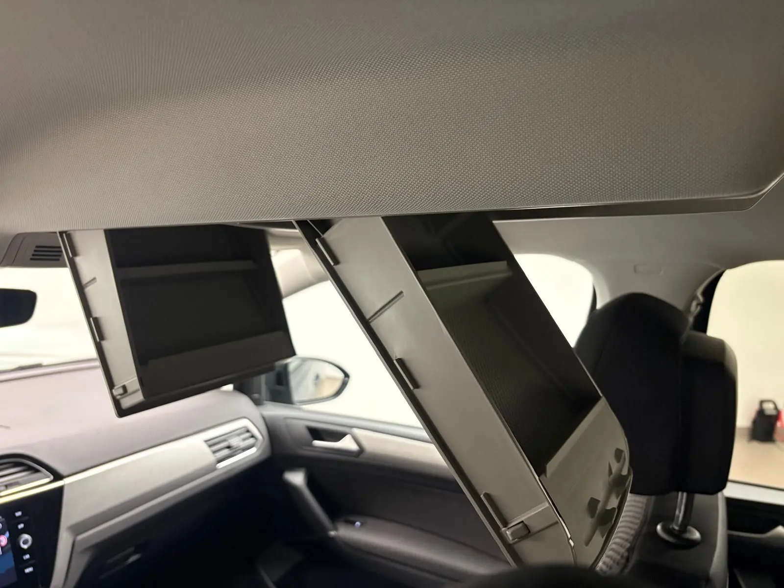 Intérieur du Volkswagen Touran gris Dauphin, vue côté passager avec deux rangements plafond ouverts au-dessus des sièges.
