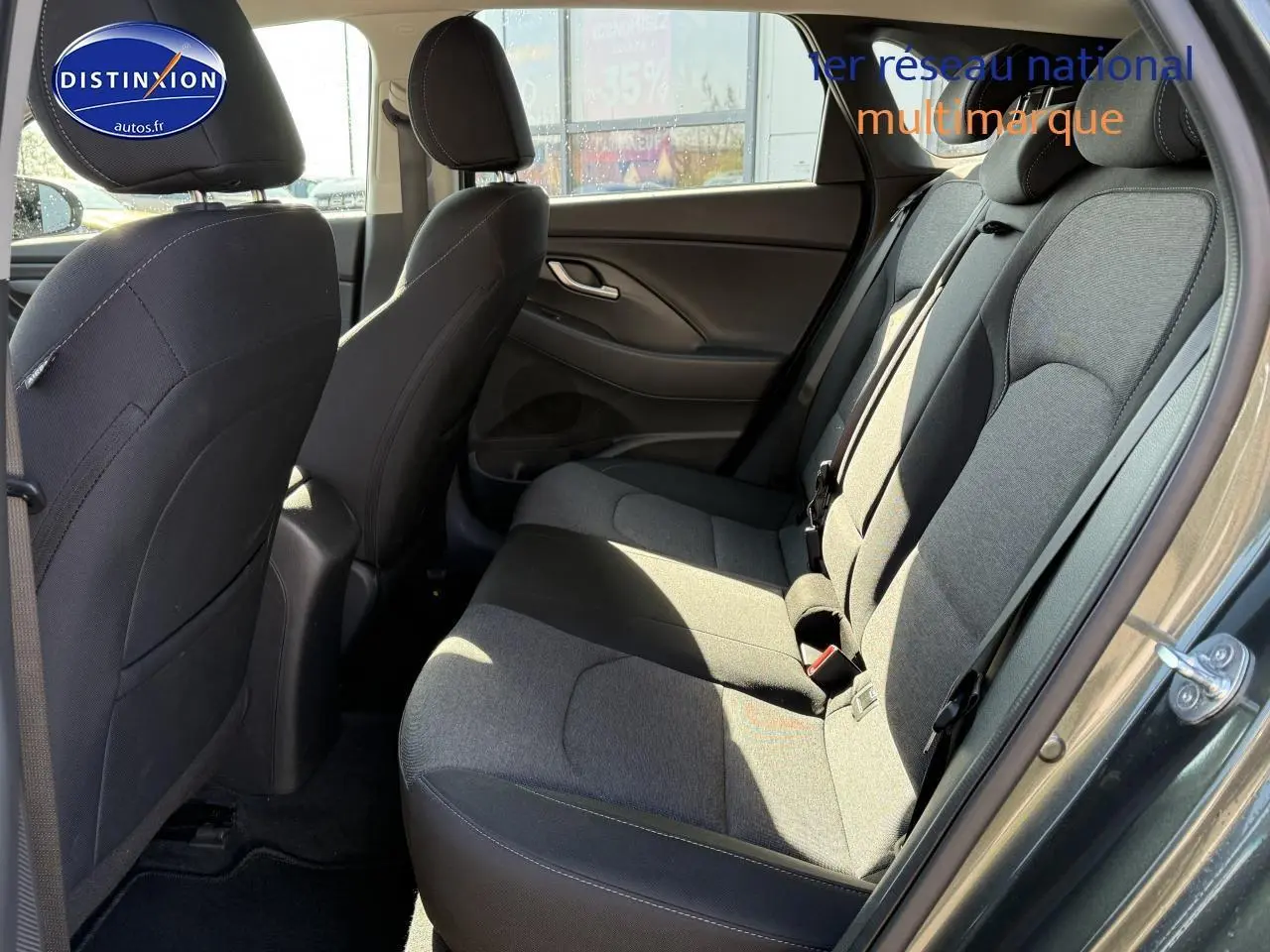 Vue côté gauche de l'habitacle arrière gris anthracite de la Hyundai i30 2024 avec sièges tissu et ceintures visibles