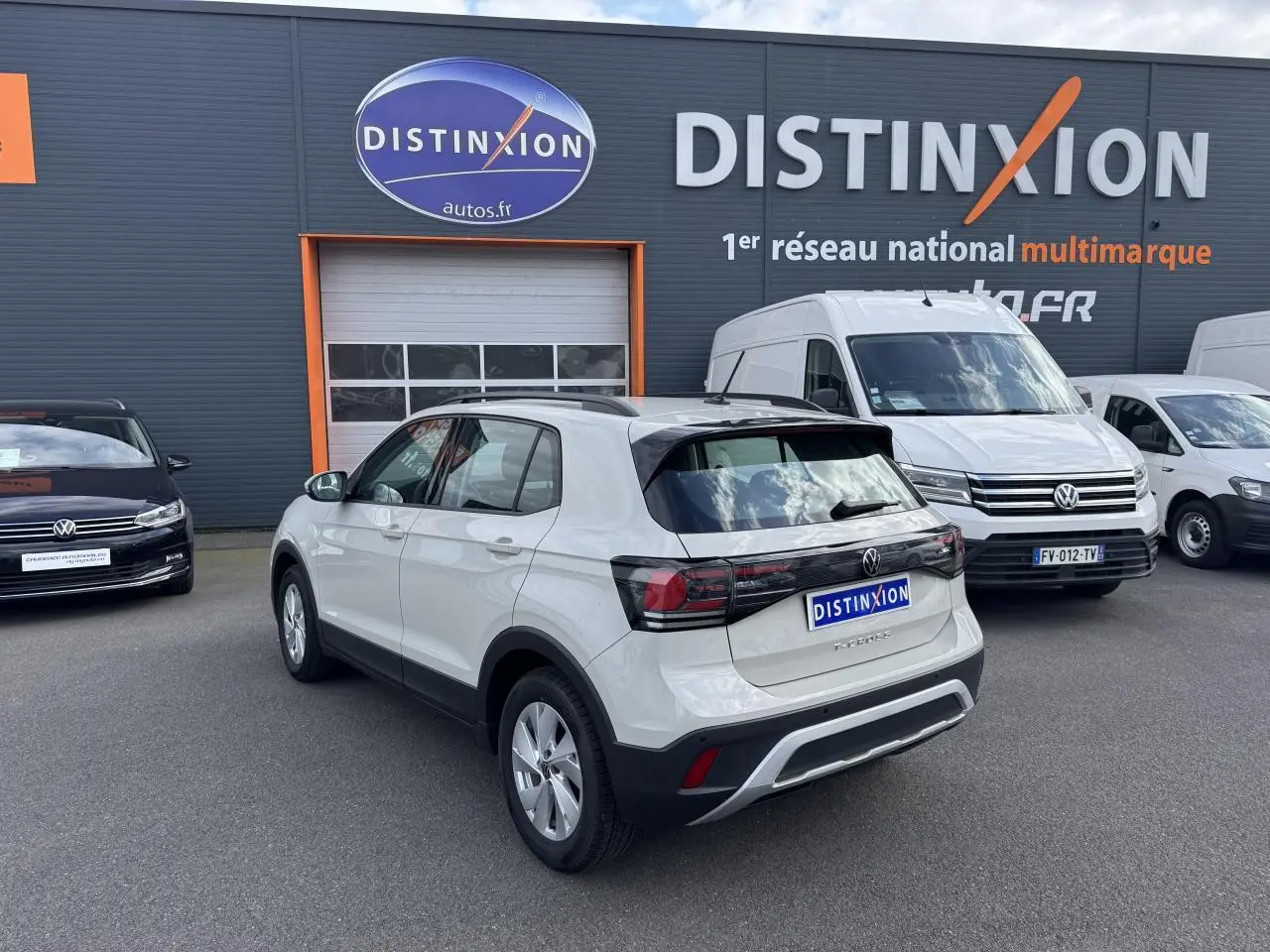 Volkswagen T-Cross gris Ascot vue 3/4 arrière droit sur parking devant un bâtiment Distinxion.